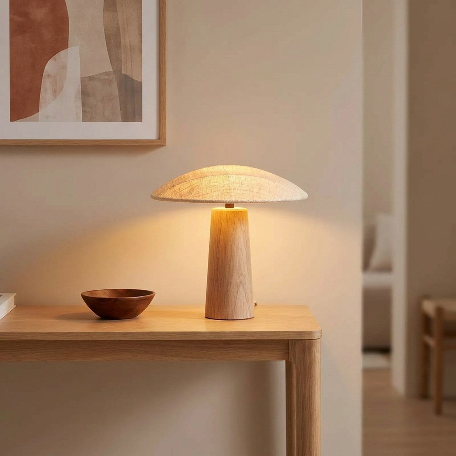 Lampe champignon en bois allumée sur une console d'entrée sous un cadre décoratif