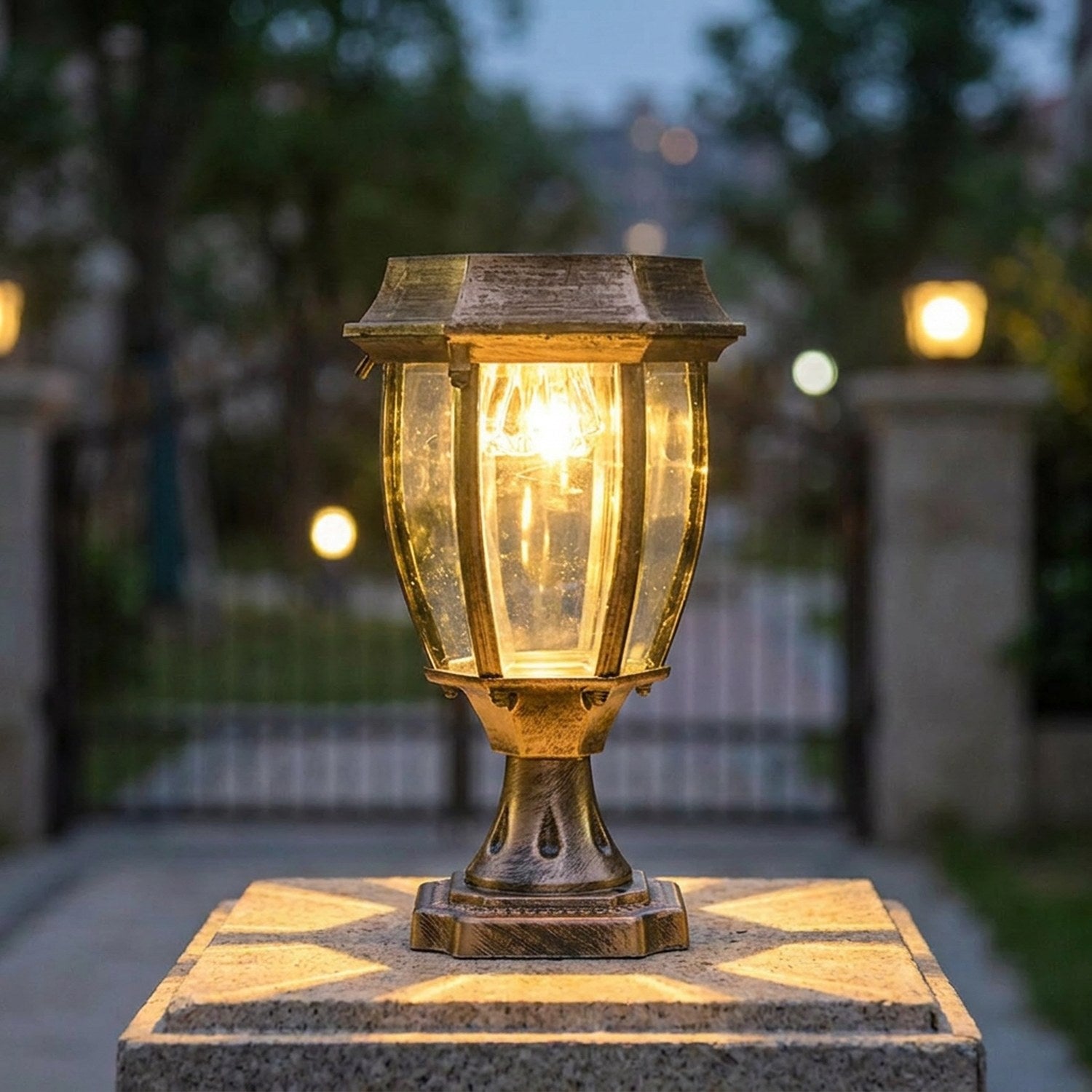 Lanterne solaire bronze posée sur un pilier de portail illuminant l'entrée à la tombée du jour