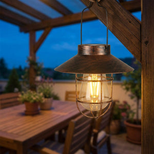 Lanterne solaire bronze allumée suspendue à une pergola sur une terrasse en soirée