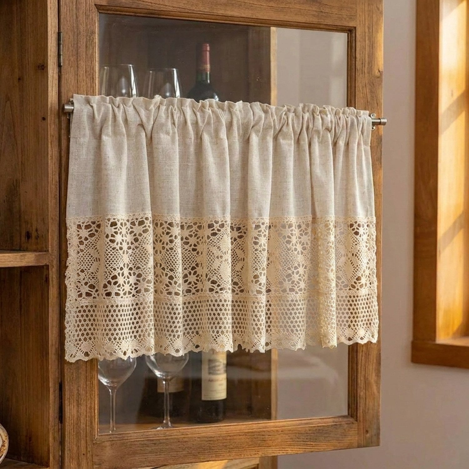 Rideau court en dentelle beige installé sur la porte vitrée d'un meuble à vin en bois