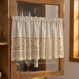 Rideau court en dentelle beige installé sur la porte vitrée d'un meuble à vin en bois