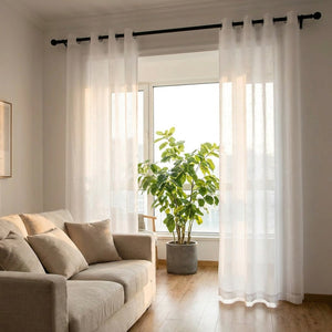 Voilage en tulle blanc à œillets dans un salon lumineux avec canapé en lin et plante verte