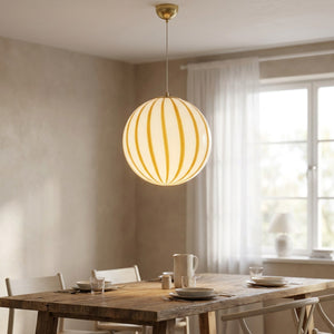 Suspension boule rayée jaune au-dessus d'une table à manger scandinave