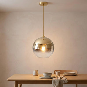 Suspension boule de verre dorée au-dessus d'une table de salle à manger scandinave