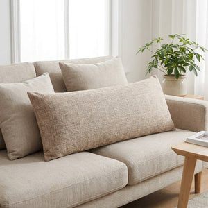 Housse de coussin longue beige sur un canapé en lin avec plante