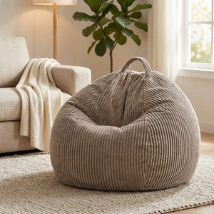 Housse de pouf poire taupe dans un coin salon avec canapé plaid et plante