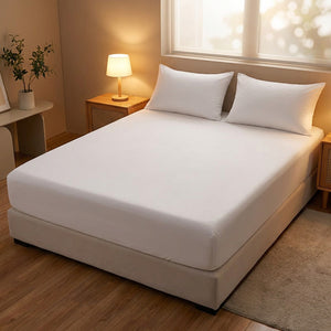 Drap-housse blanc ajusté sur un matelas dans une chambre chaleureuse avec lampe de chevet