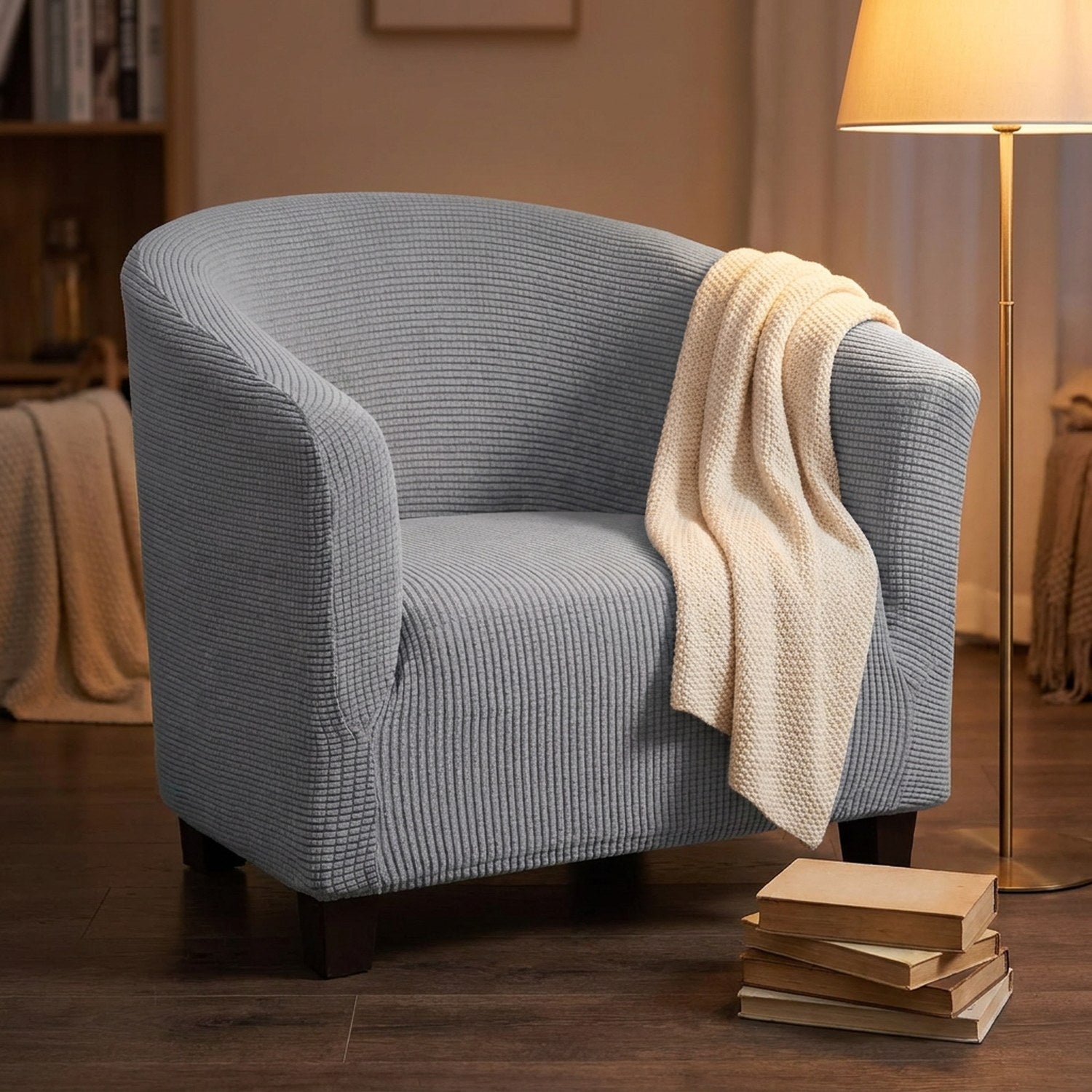 Housse de fauteuil cabriolet grise dans un coin lecture avec un plaid drapé et un lampadaire