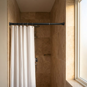 Tringle noire installée dans une niche de douche avec rideau blanc suspendu