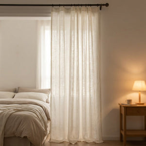 Rideau voilage en lin dans une chambre chaleureuse avec lit et lampe de chevet