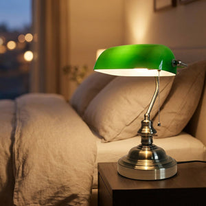 Lampe de bureau verte allumée sur une table de chevet dans une chambre