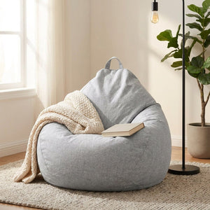 Housse de pouf poire grise avec un plaid en maille dans un coin lecture lumineux