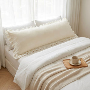 Taie de traversin crème installée sur un lit double avec plateau et tasse