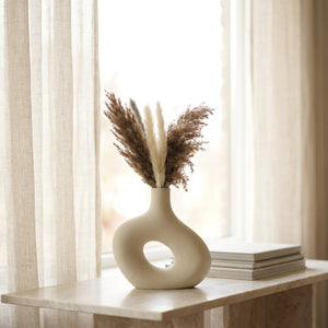 Grand vase en céramique donut blanc cassé avec pampa sur une console en marbre