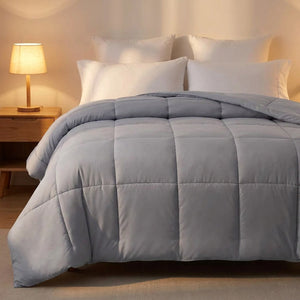 Couette moelleuse grise sur un lit avec lampe de chevet allumée