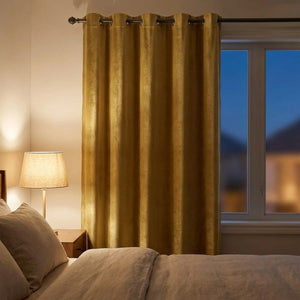 Rideau occultant velours doré dans une chambre tamisée le soir avec lampe de chevet allumée