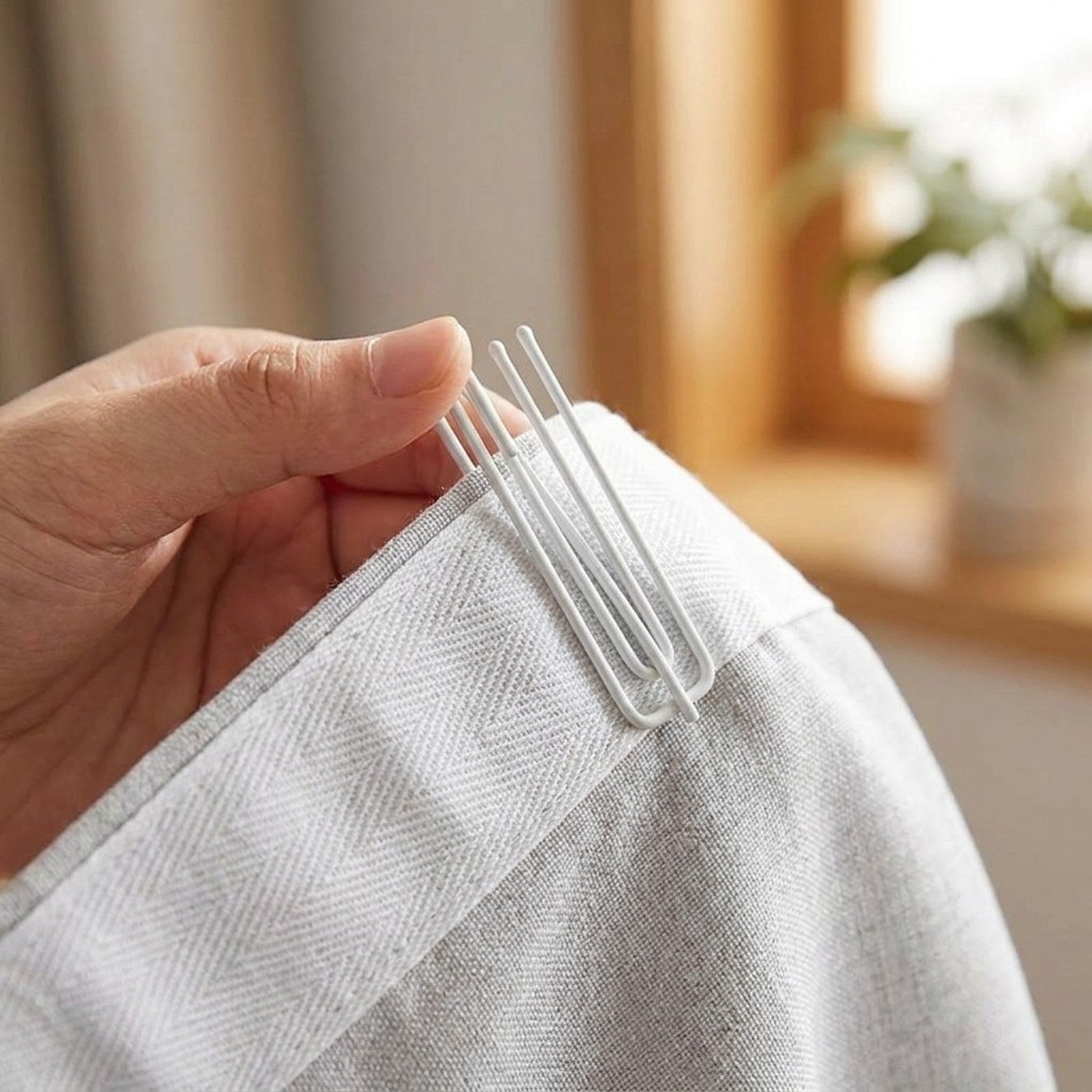 Insertion d'un crochet de rideau blanc dans le ruban fronceur en gros plan