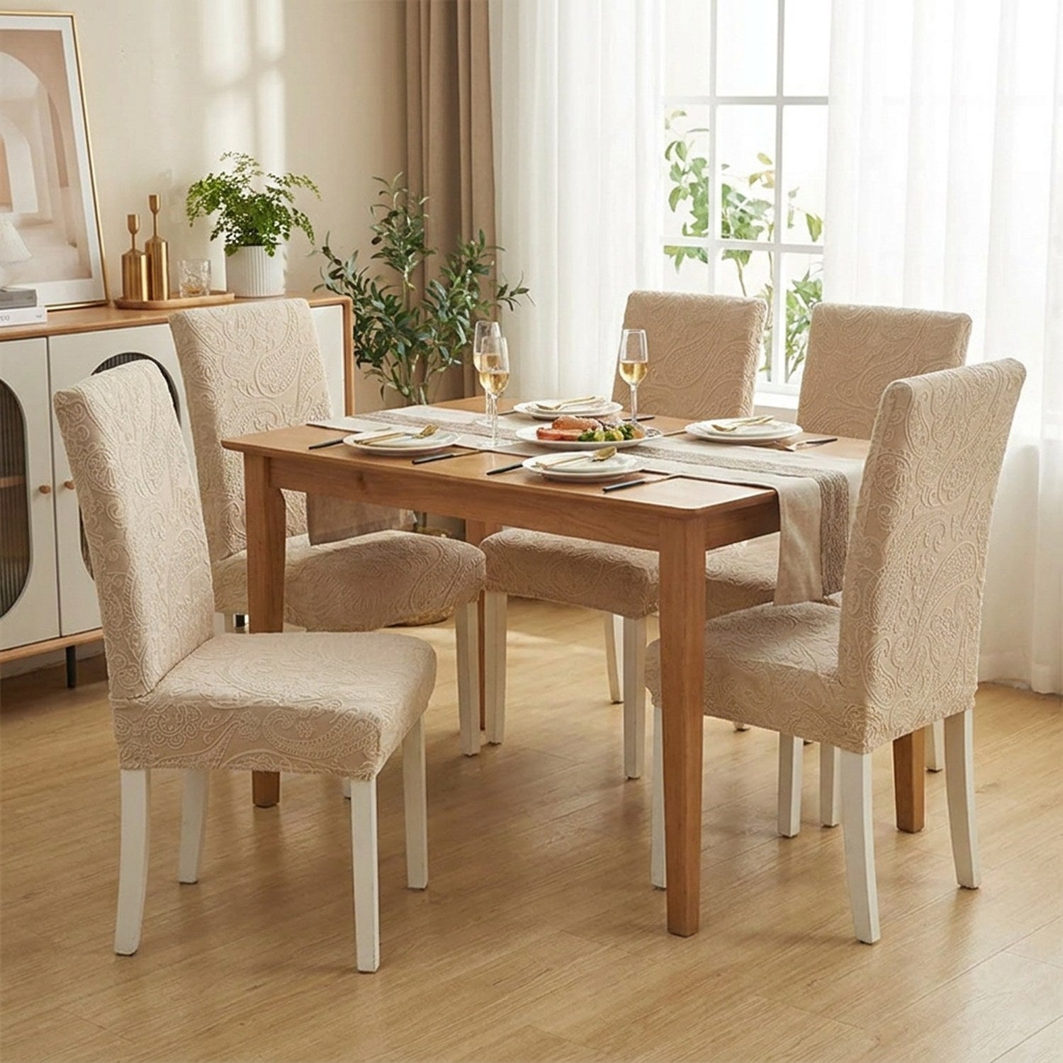 Chaises de salle à manger habillées de housses beige autour d'une table dressée