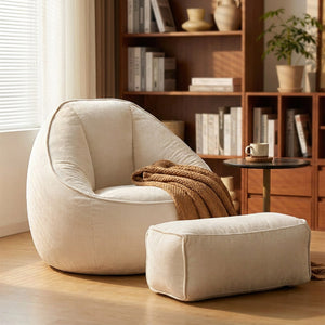 Fauteuil pouf et repose-pieds en velours côtelé blanc près d'une bibliothèque