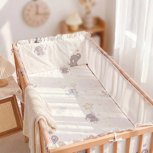 Tour de lit bébé éléphant vu de profil avec plaid en maille dans une chambre douce
