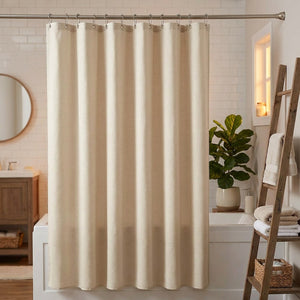 Rideau de douche en lin beige tiré devant une baignoire dans une salle de bain cosy