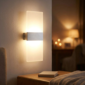 Applique murale LED argentée allumée en tête de lit dans une chambre cosy