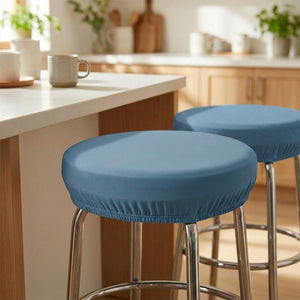 Deux tabourets de bar habillés de housses rondes bleues à un îlot de cuisine