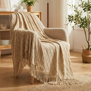 Couverture tricotée kaki à franges drapée sur un fauteuil dans un salon bohème