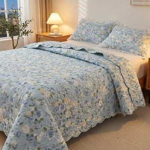 Couvre-lit fleuri bleu drapé sur un lit avec lampe de chevet chaleureuse