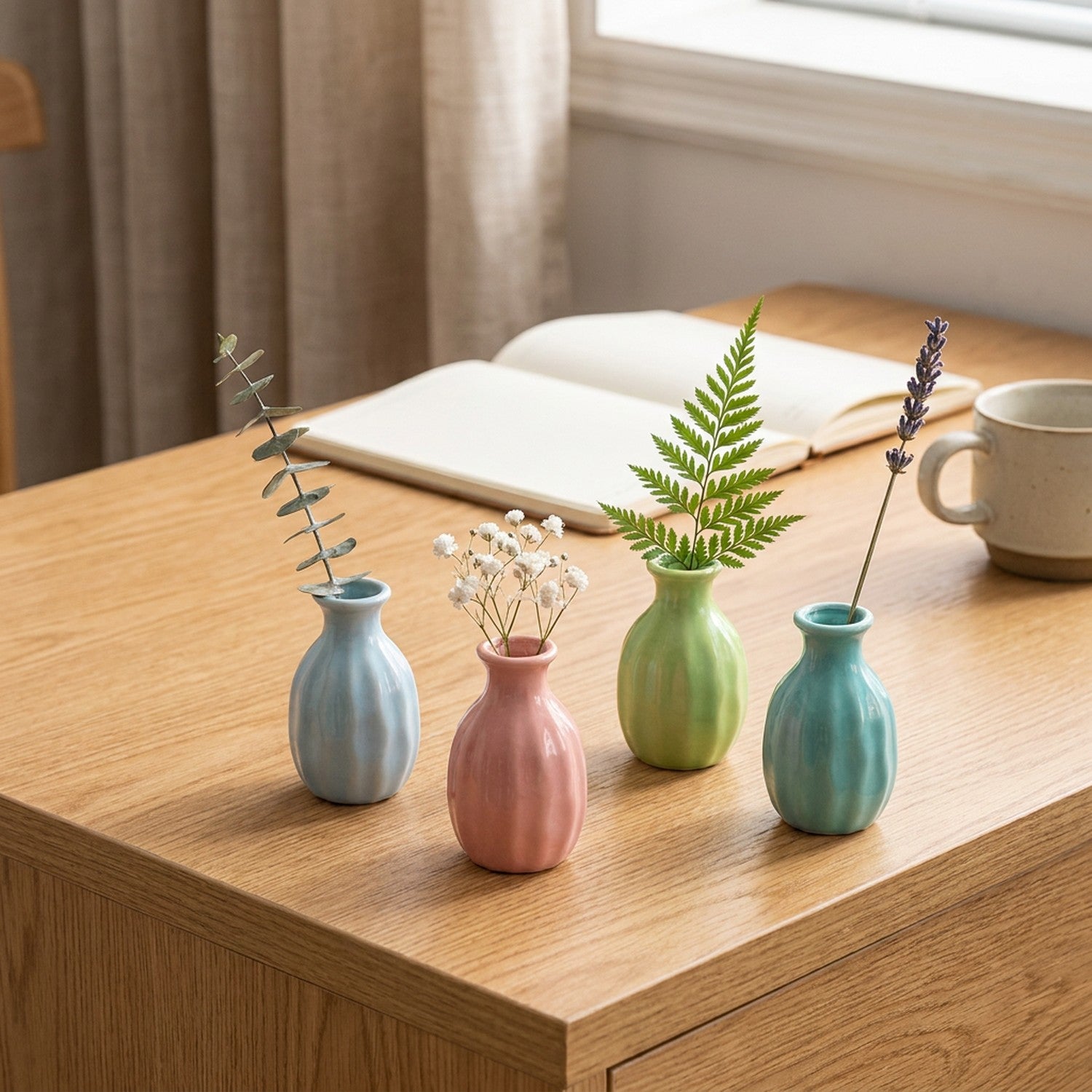 Quatre mini vases en céramique colorés groupés sur un bureau avec petites fleurs