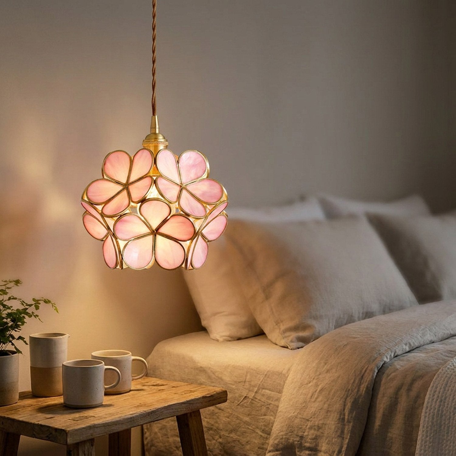 Suspension fleur en verre rose allumée en guise de chevet suspendu dans une chambre cosy