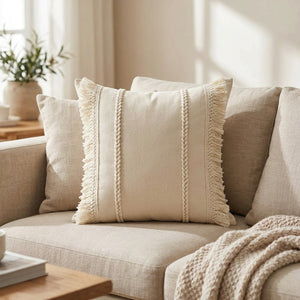 Coussin bohème beige à franges sur un canapé en lin avec des coussins neutres