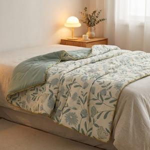 Couette d'été botanique verte drapée sur un lit avec lampe de chevet chaleureuse