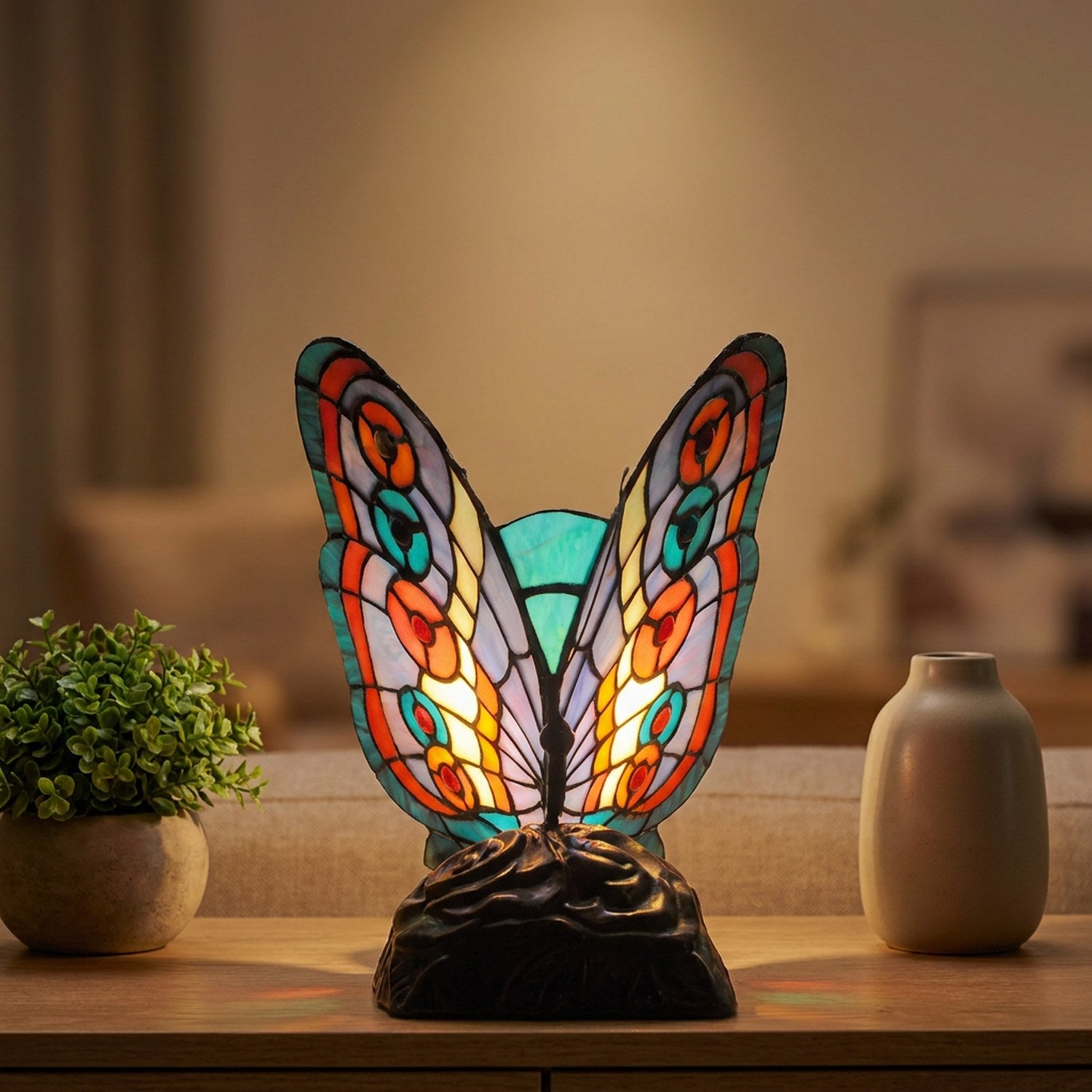 Lampe style Tiffany papillon en vitrail allumée sur une console de salon près d'une plante verte