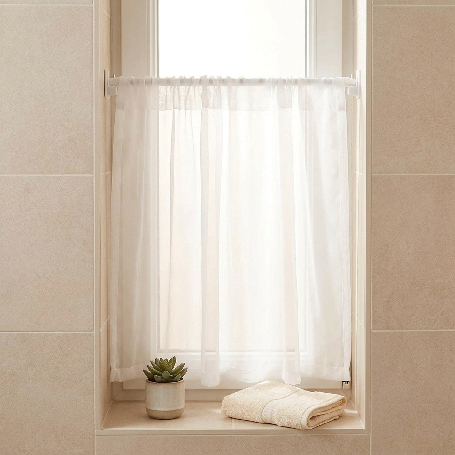 Tringle à rideau installée sur une petite fenêtre de salle de bain avec voilage