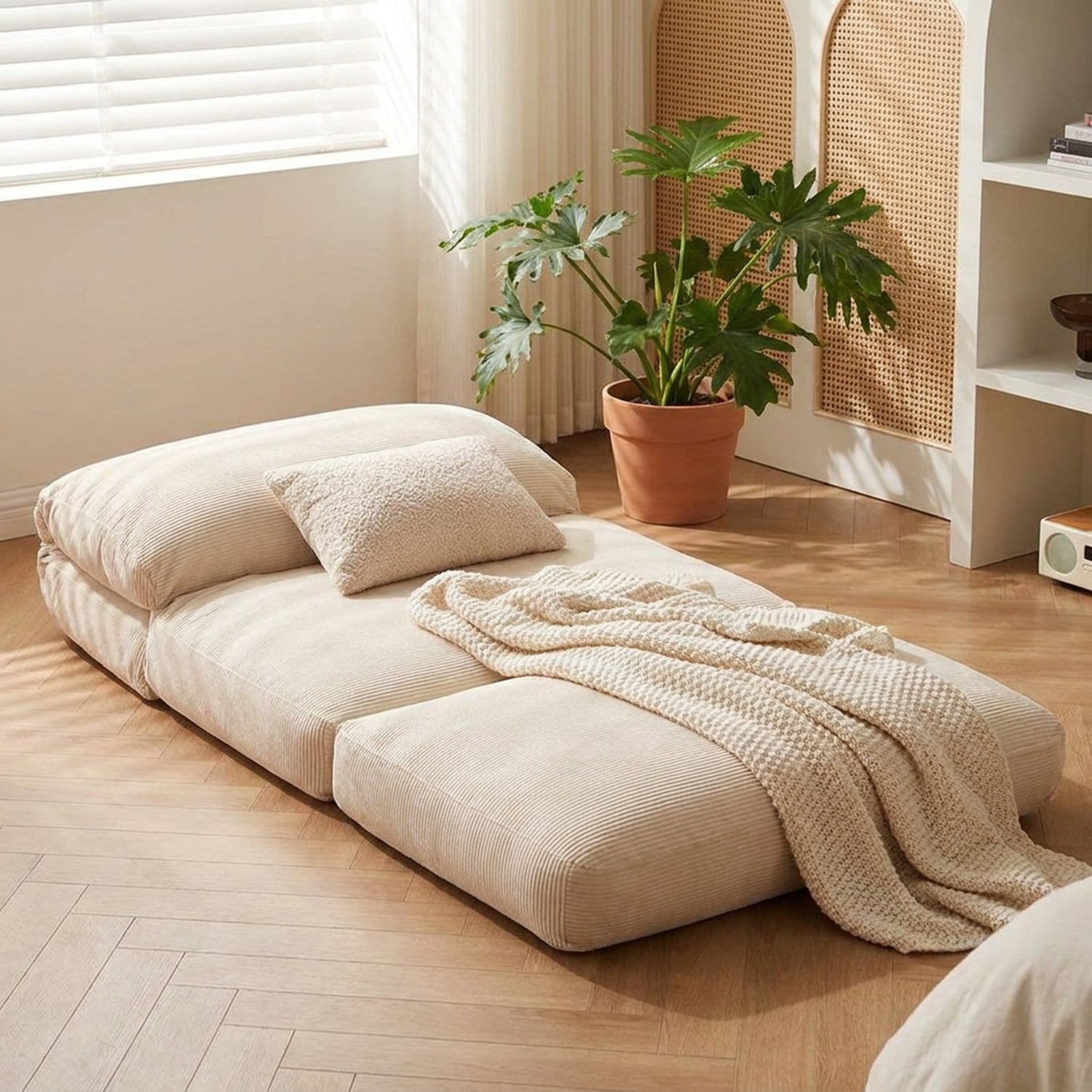 Fauteuil de sol crème déplié à plat en couchage d'appoint avec une couverture dans une chambre