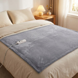 Couverture chauffante grise déployée sur un lit une place dans une chambre cosy