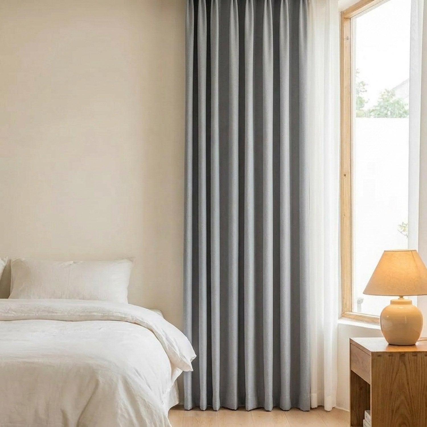 Rideau occultant gris dans une chambre chaleureuse avec lit fait et table de chevet en bois