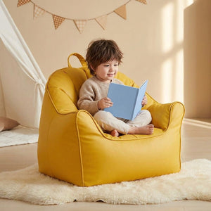 Enfant assis dans le pouf fauteuil jaune en train de lire un livre