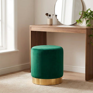 Tabouret rond en velours vert utilisé comme siège devant une coiffeuse avec miroir rond