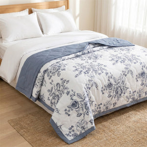 Couvre-lit matelassé d'été à roses bleues drapé sur le pied d'un lit dans une chambre lumineuse