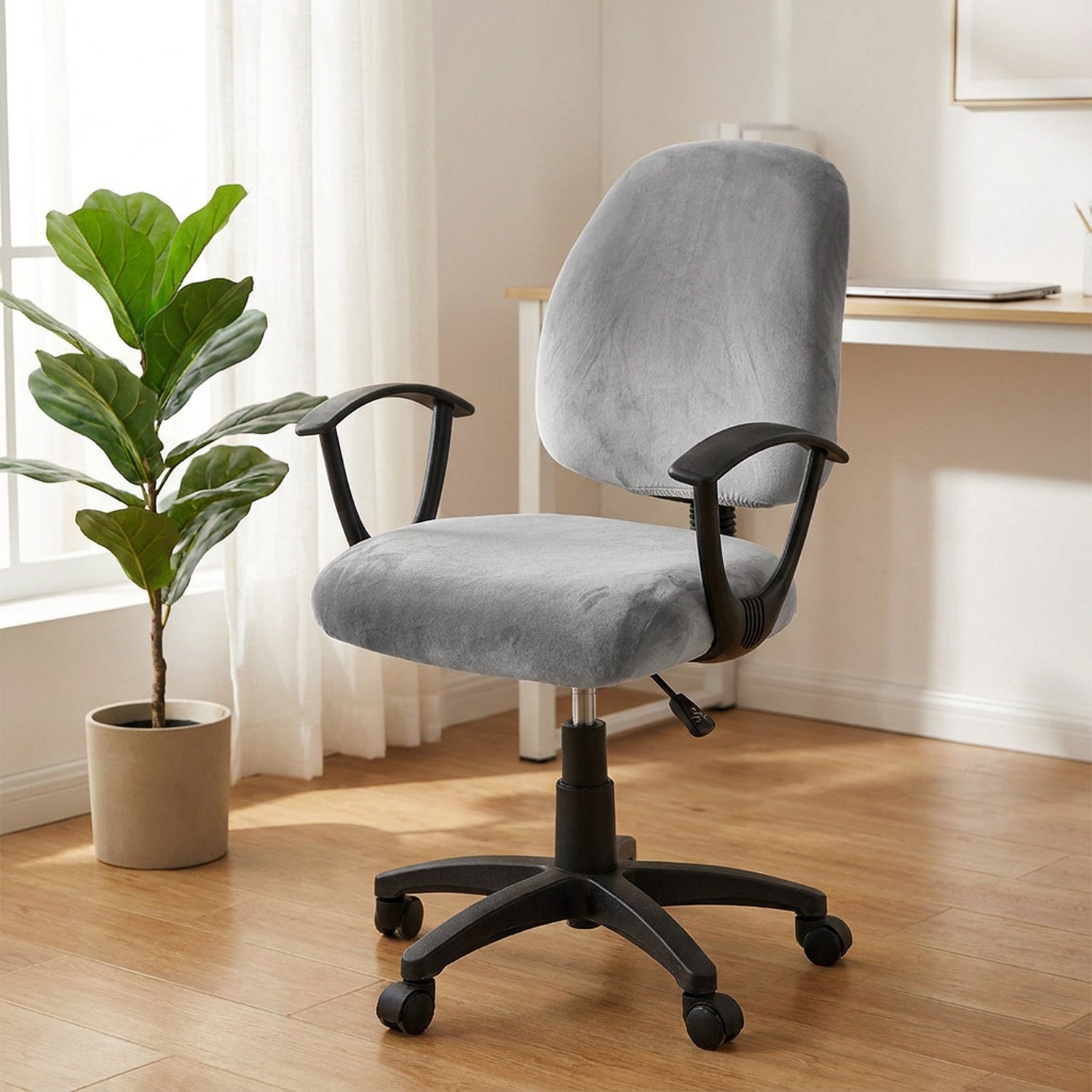 Fauteuil de bureau habillé d'une housse grise en velours pres d'une fenetre lumineuse avec une plante verte
