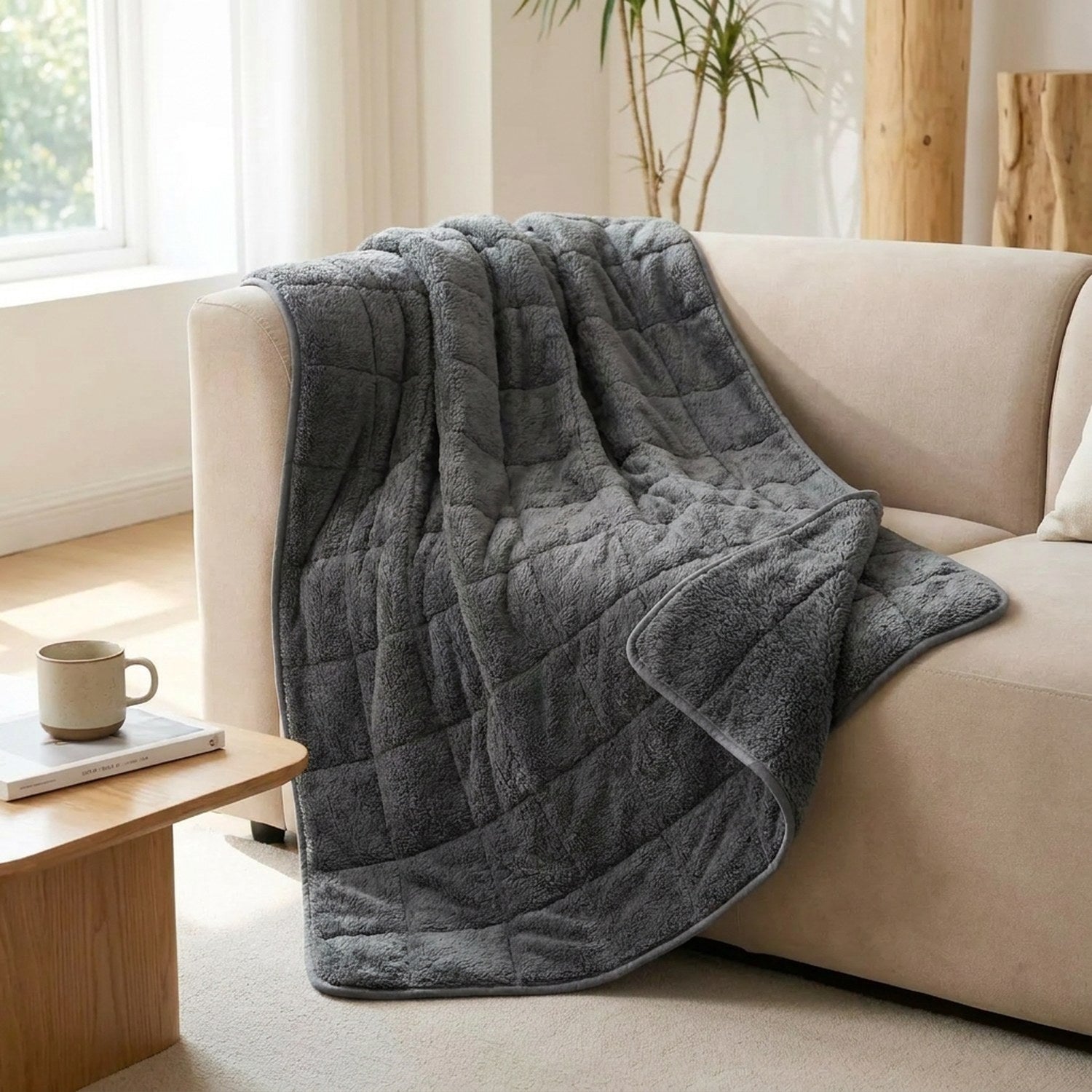 Couverture lestée grise drapée sur un canapé beige avec tasse et coussin