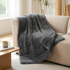 Couverture lestée grise drapée sur un canapé beige avec tasse et coussin