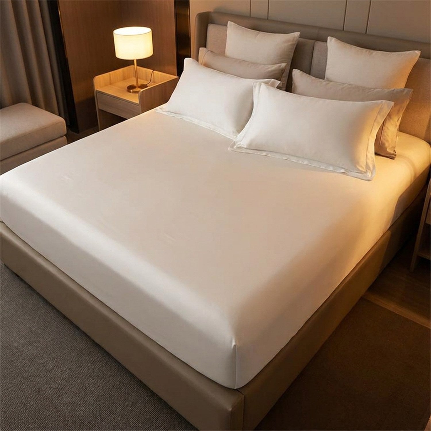 Drap-housse blanc sur un lit avec lampe de chevet allumée en ambiance cocooning