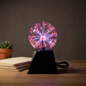 Lampe boule de plasma allumée sur un bureau avec cahiers et plante succulente