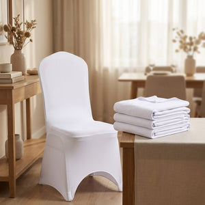 Housse de chaise blanche installée à côté d'une pile de housses pliées sur une console en bois