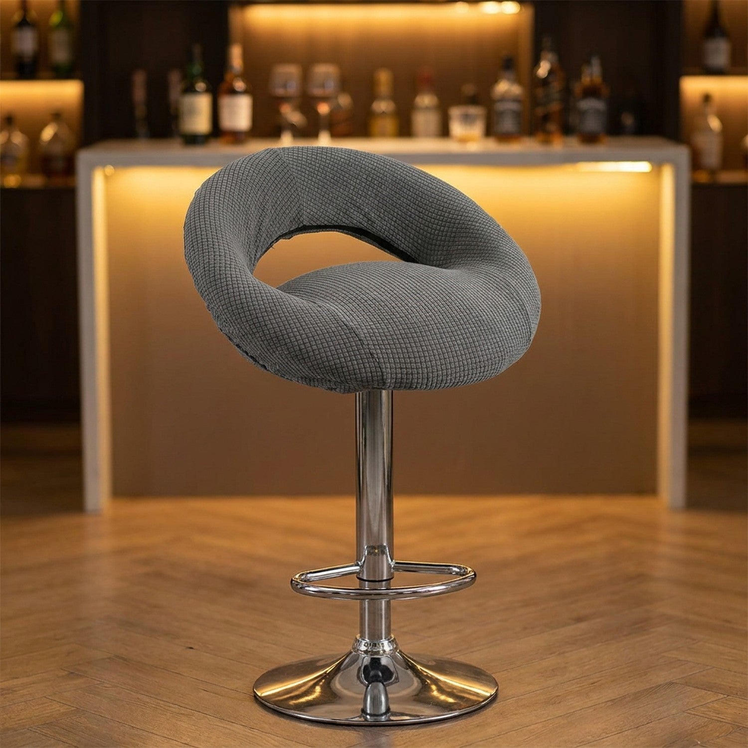 Housse de tabouret de bar demi-lune grise sur un tabouret devant un bar chaleureux