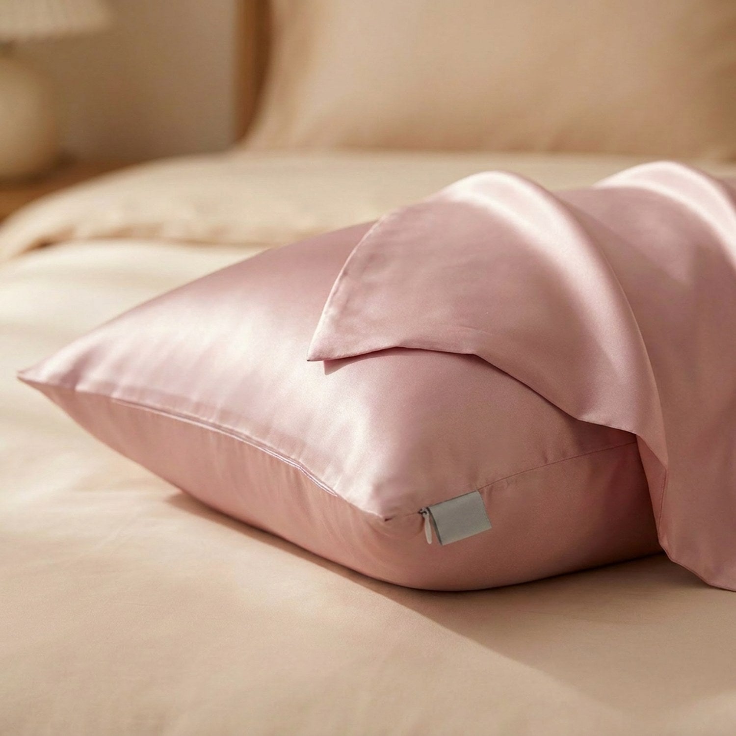 Taie d'oreiller en soie rose en gros plan sur un lit montrant le tissu satiné replié