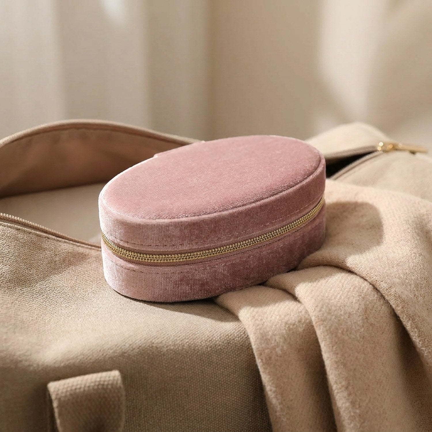 Boîte à bijoux en velours rose posée sur un sac de voyage